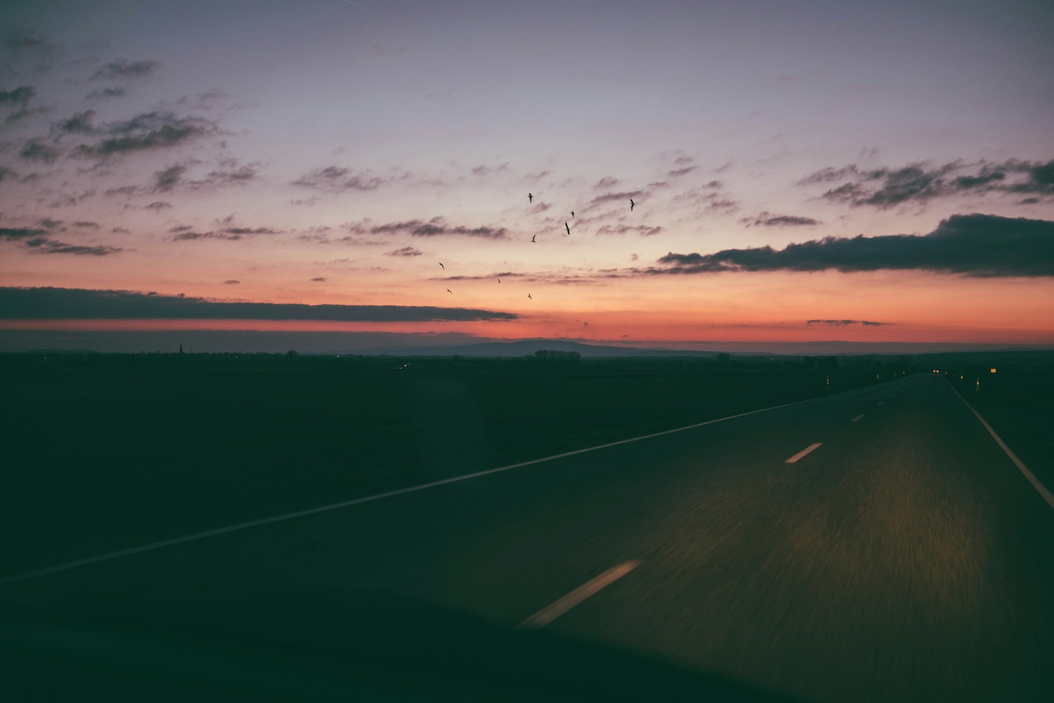 A new car driving into the sunset on an open road